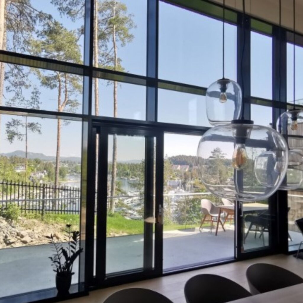 Modern curtain wall design with expansive glass windows offering scenic views, seamlessly blending indoor and outdoor living spaces in Dubai, with contemporary lighting fixtures by Elegant Rooms